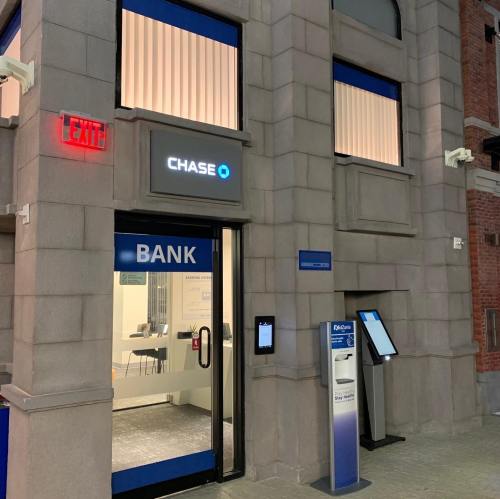 Exterior view of a Chase Bank branch with an exit sign and an ATM outside.