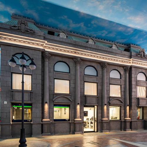 Historic building with columns and large windows, illuminated at night, featuring a modern entrance and street lamp.