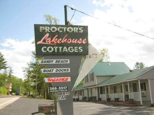 Sign for Proctor's Lakehouse Cottages, featuring amenities like sandy beach and boat docks, with a "Vacancy" notice.