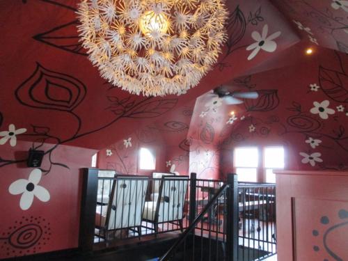 A vibrant restaurant interior with red walls adorned with floral designs and a unique chandelier.