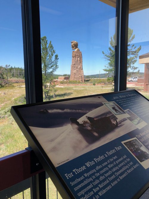 View from a building showcasing a large statue outside, with informational display in the foreground.