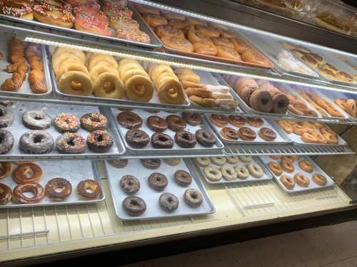 A display case filled with various donuts, including glazed, chocolate, and sprinkled varieties.