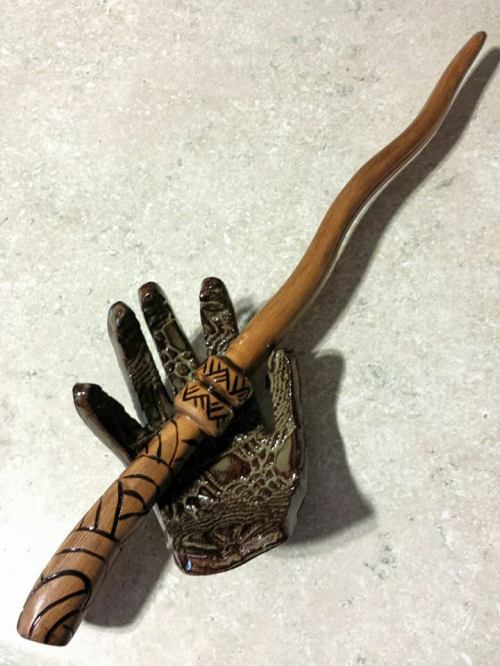 A carved wooden wand resting on a decorative hand-shaped stand.