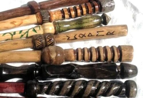 A collection of intricately carved wooden sticks with various designs and patterns, arranged in two rows.