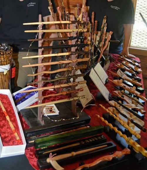 A display of various handcrafted wands arranged on a table, with labels and decorative elements.