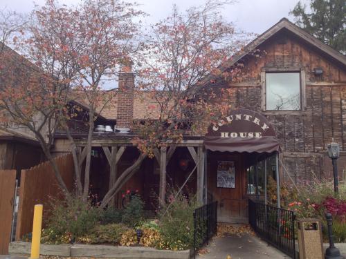 A rustic building with a sign reading "Country House," surrounded by autumn foliage and flowers.