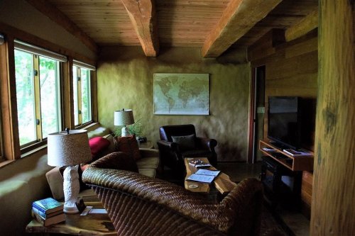 Cozy living room with wooden beams, a map on the wall, and comfortable seating, illuminated by natural light.