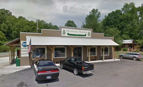 Exterior view of Mentone Market, a rustic building with a sign, parked cars, and trees in the background.