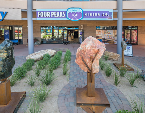 Exterior view of Four Peaks Mining Co. with large rock displays and a landscaped entrance.