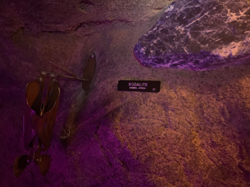 A sign labeled "Sodalite" displayed on a rocky surface with purple lighting in a cave-like setting.