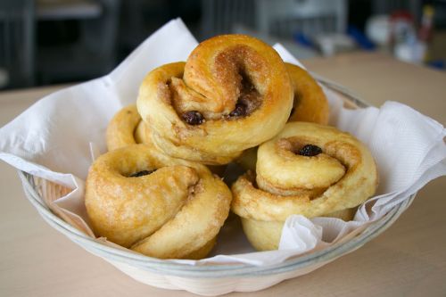 A basket of freshly baked cinnamon rolls with a golden-brown crust and a hint of raisins.