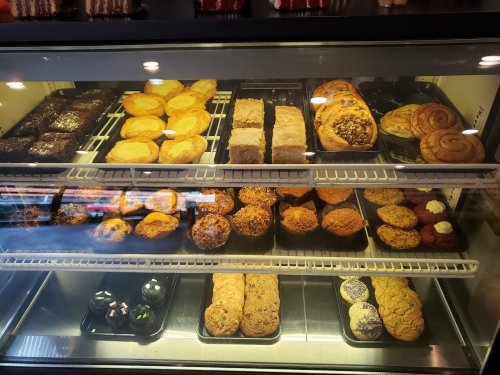 A display case filled with various baked goods, including cookies, pastries, and brownies.