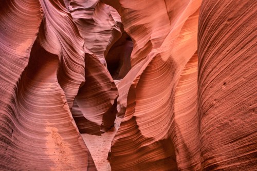 A stunning view of Antelope Canyon's swirling red rock formations and smooth, wavy textures illuminated by natural light.