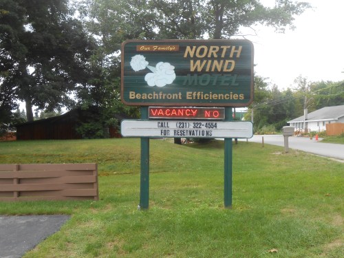 Sign for North Wind Motel with "Vacancy No" and contact number for reservations. Beachfront location indicated.