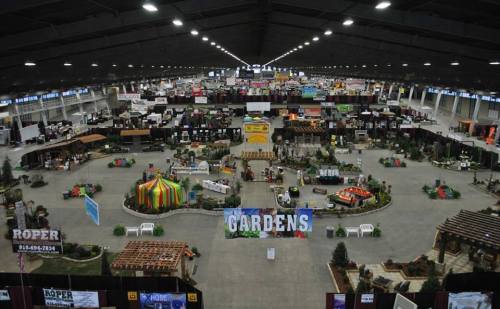 A wide view of an indoor exhibition space filled with booths, displays, and decorations for a garden show.