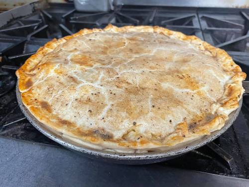A freshly baked pie with a golden-brown crust, resting on a stovetop.