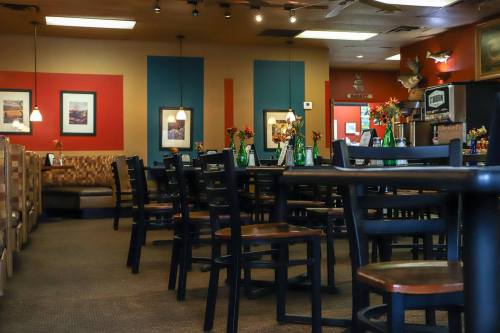 A cozy restaurant interior with empty tables, colorful walls, and floral centerpieces.