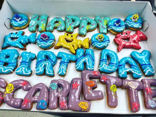 Colorful birthday cookies spelling "Happy Birthday Scarlette," decorated with ocean-themed designs and vibrant icing.