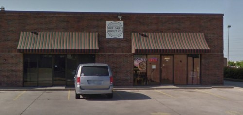 Exterior of "Our Daily Donut Co." with striped awnings, a van parked outside, and an "Open" sign in the window.