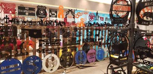 A display of various metal signs with different designs and messages, arranged in a colorful indoor setting.