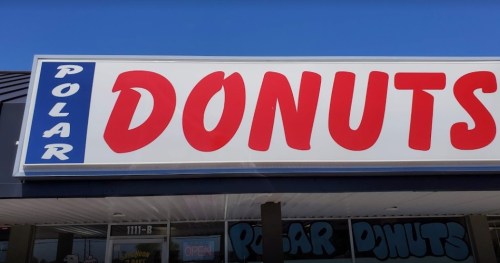 Sign for "Polar Donuts" with bold red letters on a blue and white background. Storefront visible below.