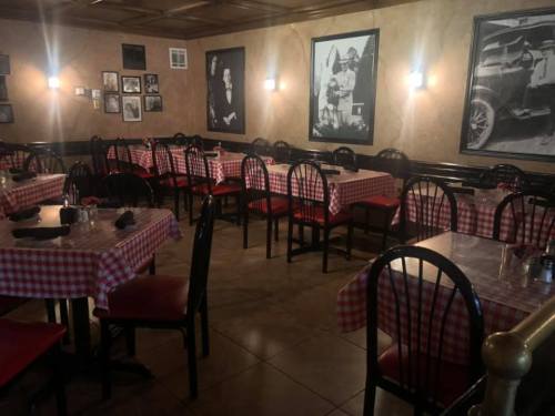 Cozy restaurant interior with checkered tablecloths, black chairs, and vintage black-and-white photos on the walls.