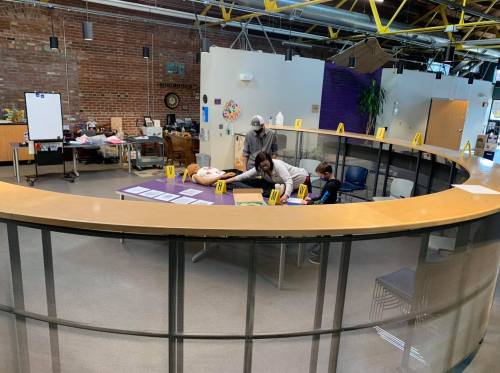 Two people work at a circular table in a modern, open space with brick walls and colorful decorations.