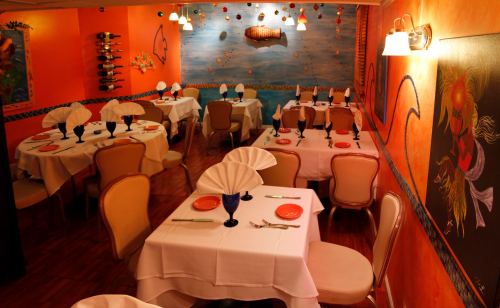 Cozy restaurant interior with orange walls, neatly set tables, and colorful decor, creating a vibrant dining atmosphere.