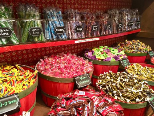 A colorful display of various candies in baskets and jars, including lollipops, taffy, and wrapped sweets.