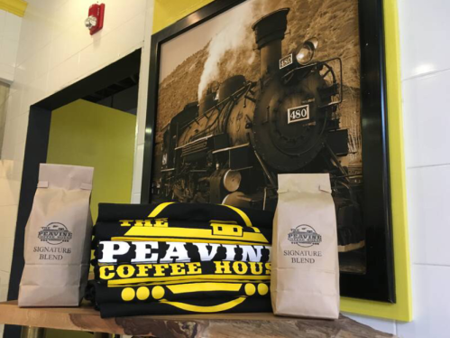 A coffee shop display featuring bags of coffee and a vintage train photo on the wall.