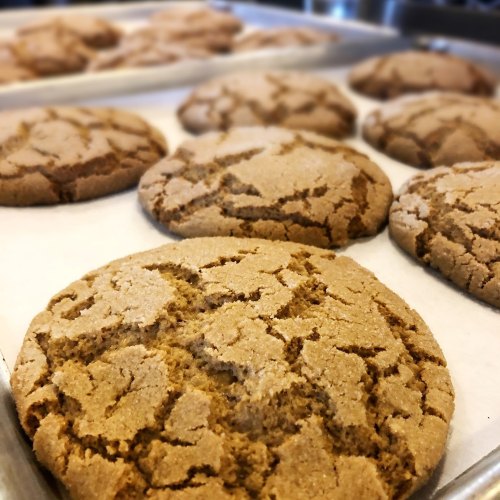 Freshly baked cookies on a tray, featuring a cracked surface and golden-brown color.
