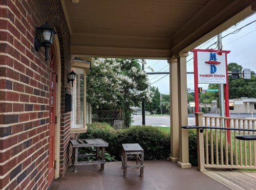 View of a porch with wooden benches, brick walls, and a sign for "Mason Dixon" in the background.