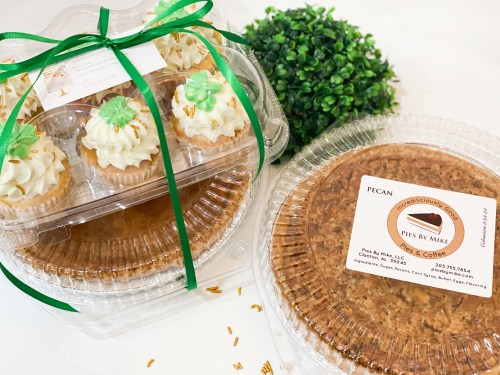 Two dessert containers: one with cupcakes topped with green decorations and another with a pecan pie, both labeled.