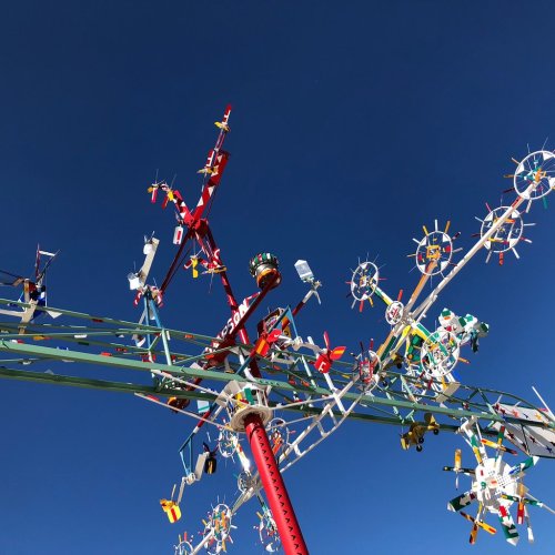 Colorful kinetic sculpture with various shapes and designs against a clear blue sky.