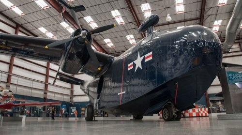 A vintage military aircraft displayed in a hangar, featuring a dark blue exterior and a prominent star insignia.