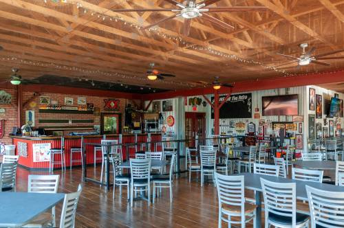 Interior of a casual restaurant with wooden floors, tables, and a bar adorned with vintage decor and memorabilia.
