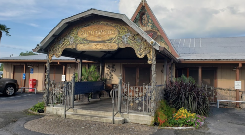 A charming building entrance with decorative architecture, surrounded by colorful flowers and greenery.