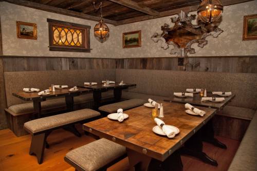 Cozy restaurant interior with wooden tables, cushioned benches, and warm lighting, featuring decorative wall art.