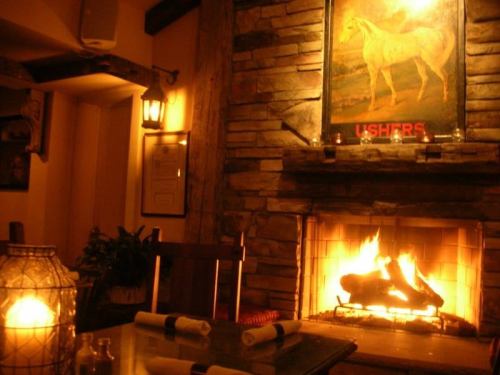 Cozy interior with a stone fireplace, a painting of a horse, and warm lighting creating a welcoming atmosphere.