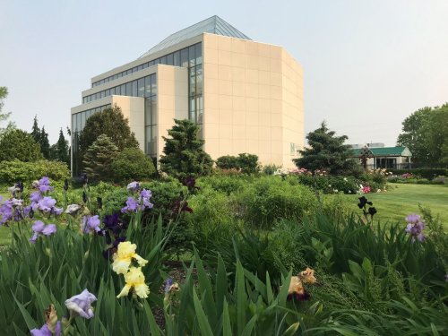 A modern building surrounded by lush greenery and colorful flowers in a garden setting.