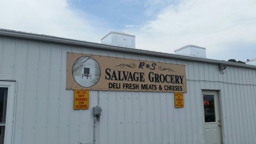 Sign for R&S Salvage Grocery featuring "Deli Fresh Meats & Cheeses" on a white building with an open sign.