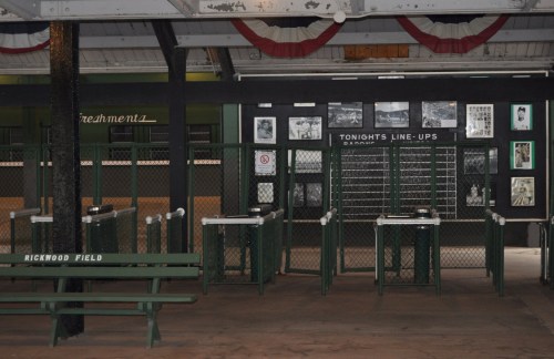 Interior of Rickwood Field, featuring turnstiles, benches, and historical photos on the walls.