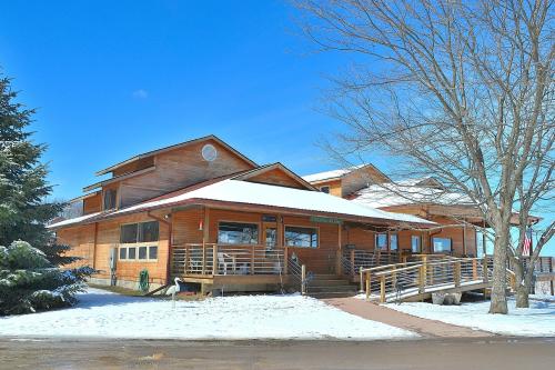 A wooden building with a sloped roof, surrounded by snow and trees, under a clear blue sky.