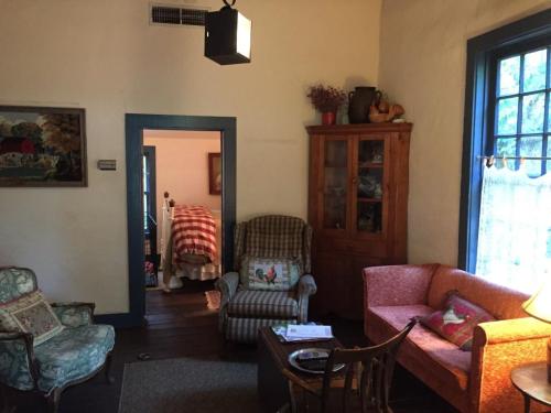 Cozy living room with vintage furniture, a wooden cabinet, and a view into a bedroom with a striped bedspread.