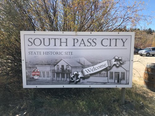Sign for South Pass City State Historic Site, featuring a welcome message and historic building illustrations.