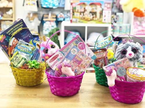 Three colorful baskets filled with toys, games, and plush animals, set against a playful store background.