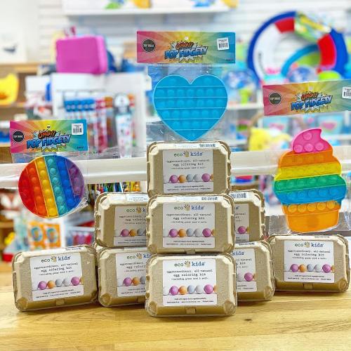 Colorful sensory toys displayed on a wooden table, including pop fidget toys and eco-friendly egg-shaped toys.