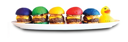 Colorful mini burgers with cheese on a white platter, alongside a yellow rubber duck.