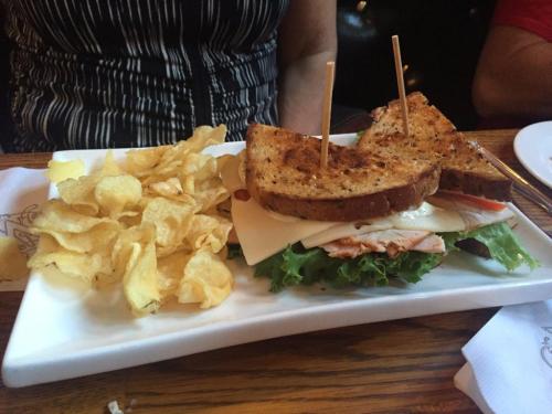 A sandwich with turkey, cheese, and lettuce, served with a side of potato chips on a white plate.