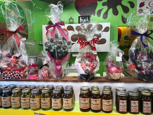 Colorful gift baskets and jars of preserves displayed on a counter, decorated with ribbons and hearts.